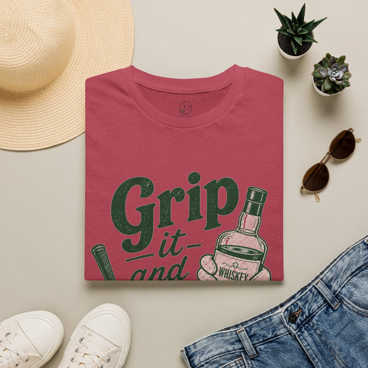 Grip It and Sip It funny golf whiskey shirt, Heather Cardinal red, folded flat lay styled with a straw sun hat, sunglasses and sneakers