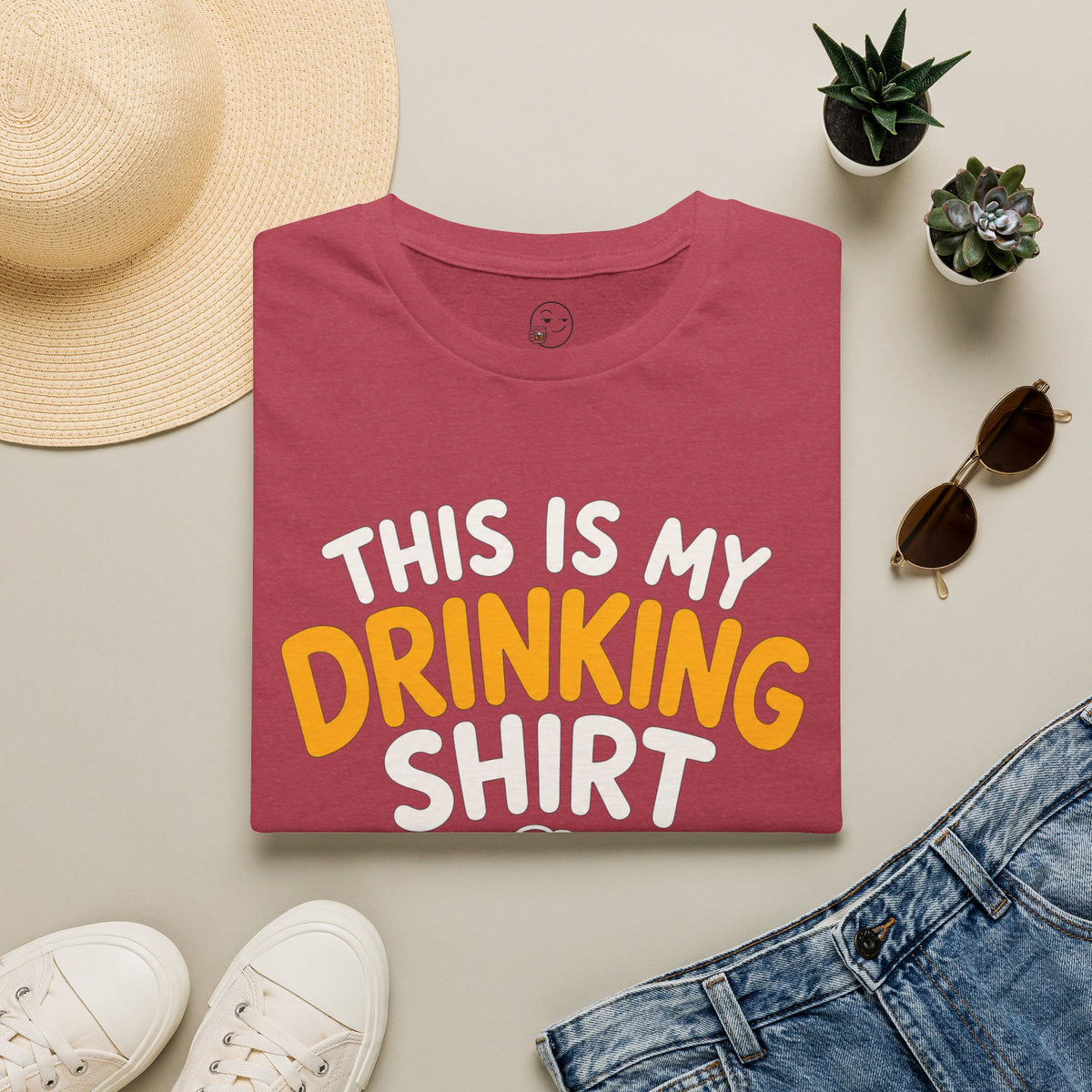 This Is My Drinking Shirt, Heather Cardinal red, folded flat lay styled with a straw hat, sunglasses, sneakers and denim