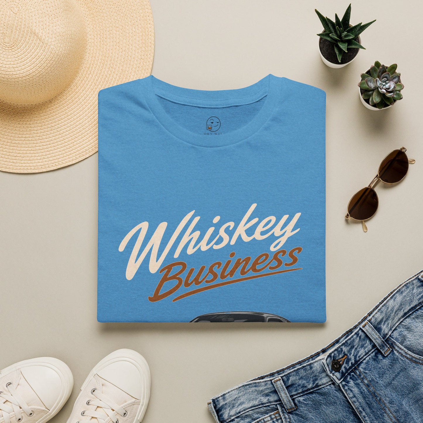 Whiskey Business Shirt, Heather Sapphire blue, folded flat lay styled with a straw hat, sunglasses, sneakers and denim