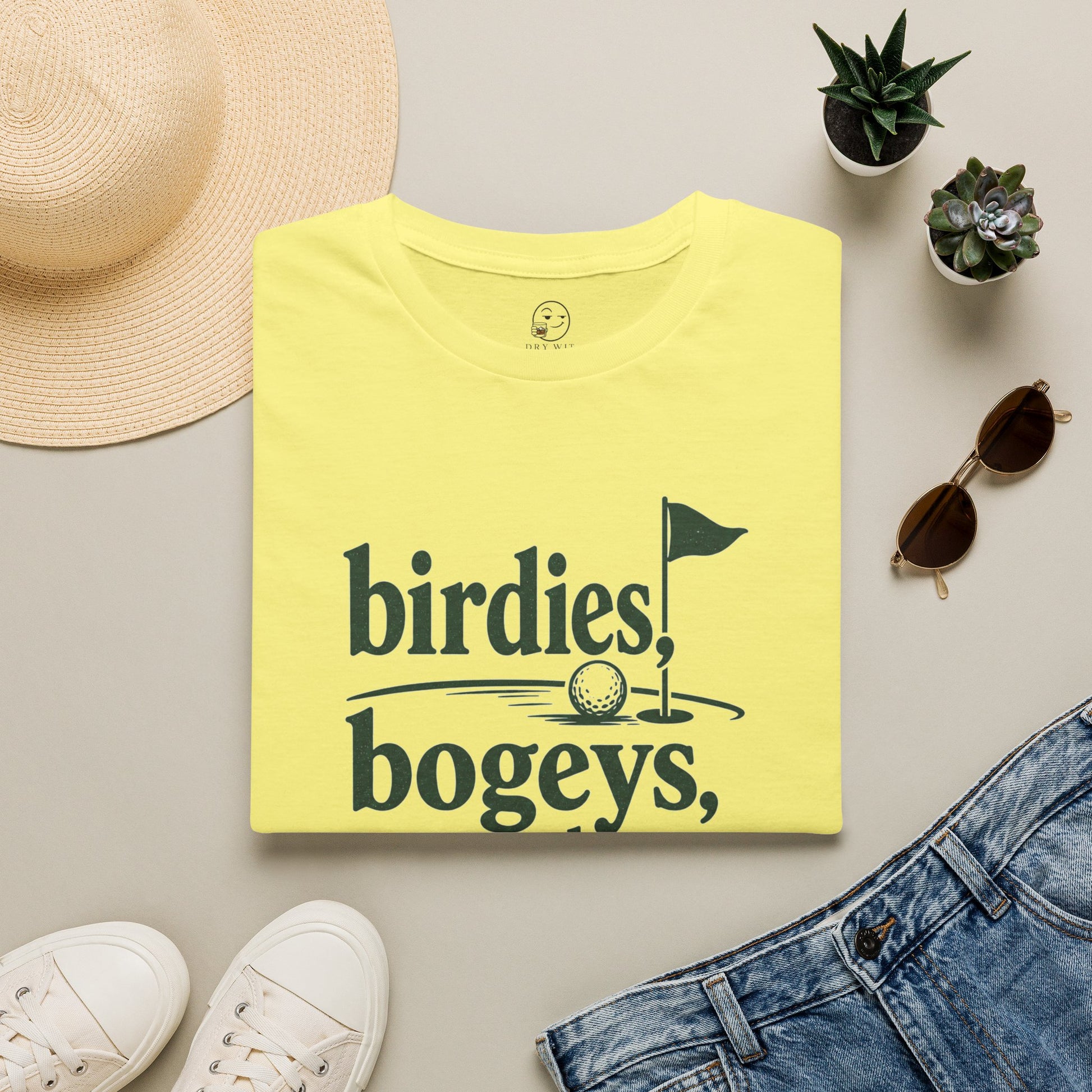 Birdies, Bogeys, and Bourbon Shirt, Cornsilk pale yellow, folded flat lay styled with a straw hat, sunglasses, sneakers and denim