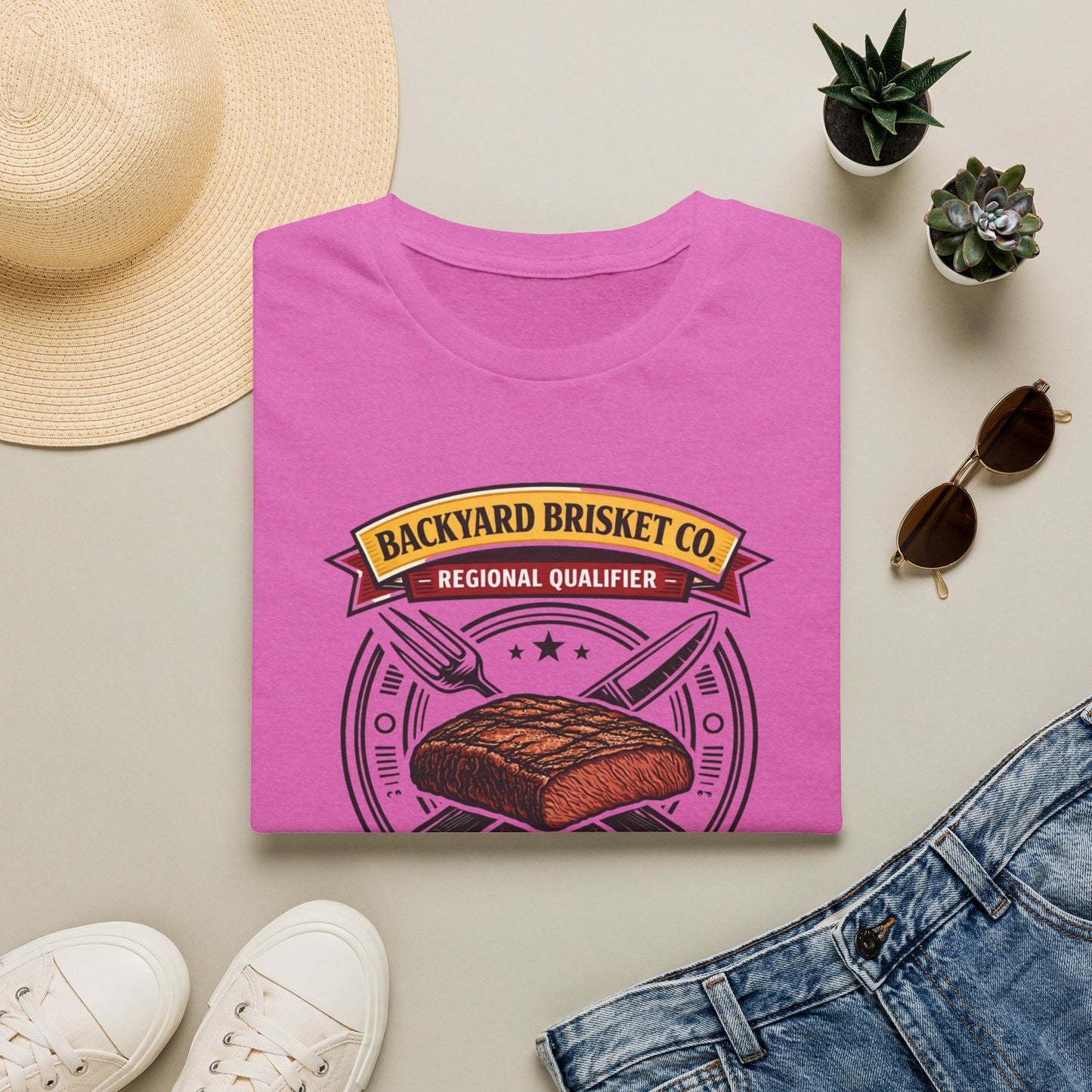 Backyard Brisket Co. Shirt, Heather Berry pink, folded flat lay styled with a straw hat, sunglasses, sneakers and denim