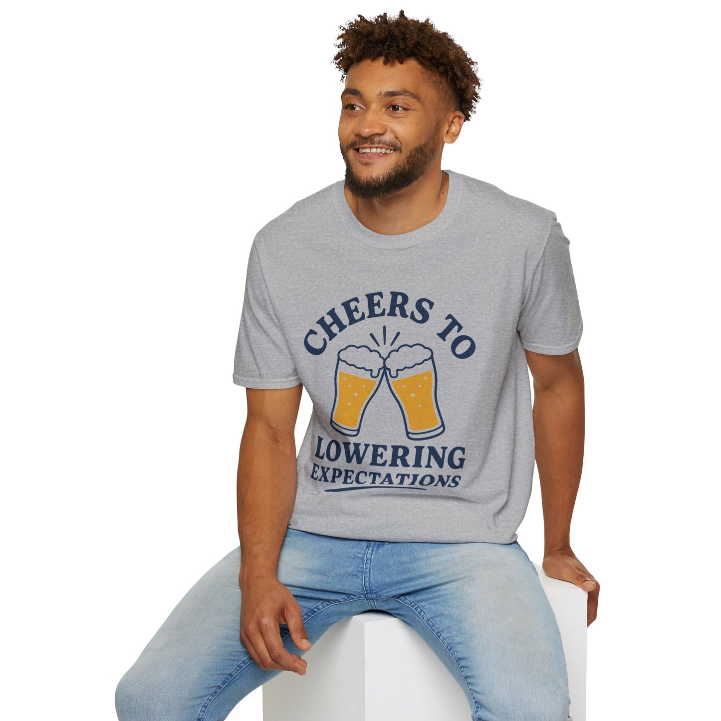 Cheers to Lowering Expectations Shirt, Sport Grey, worn by a model seated on a white block