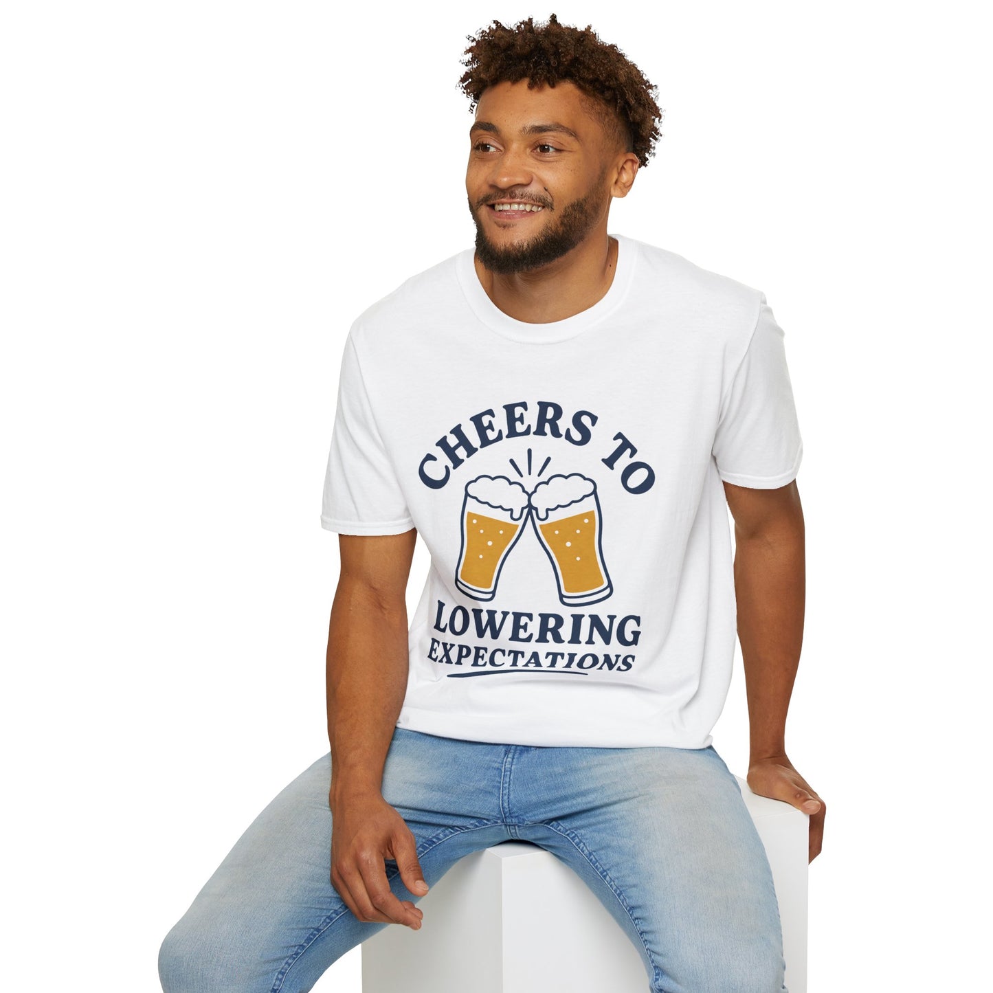 Cheers to Lowering Expectations Shirt, White, worn by a model seated on a white block