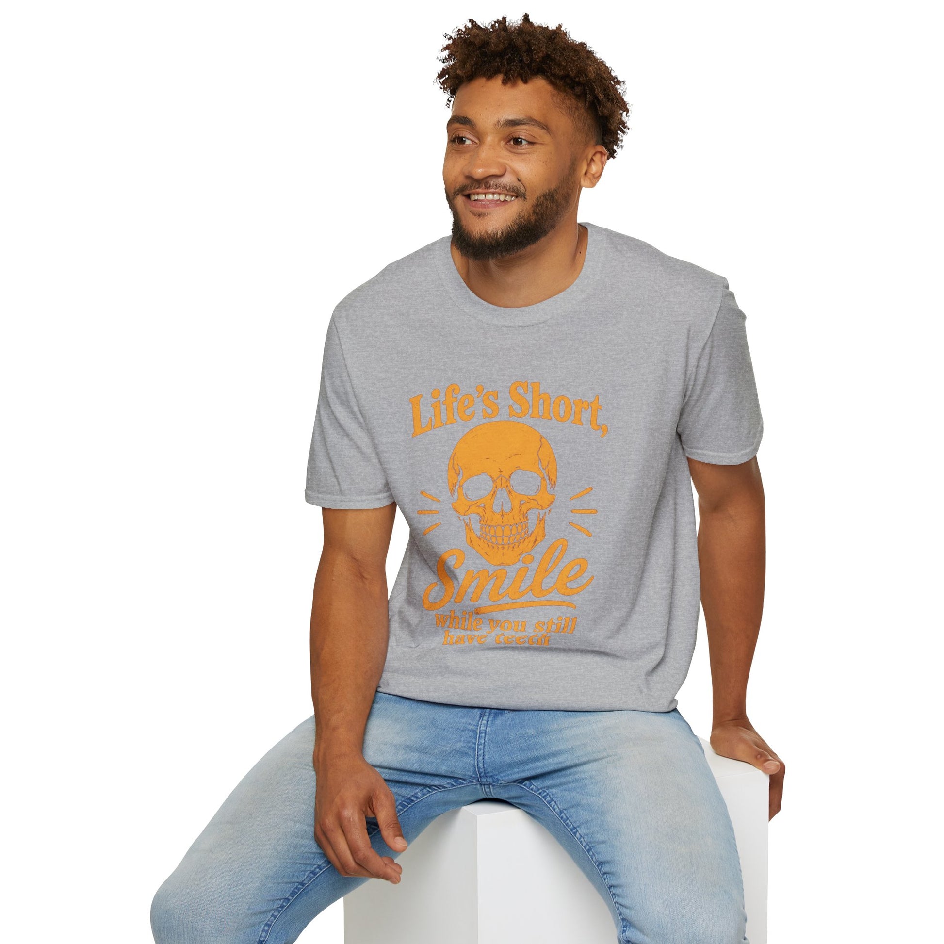 Life's Short, Smile While You Have Teeth Shirt, Sport Grey, worn by a model seated on a white block