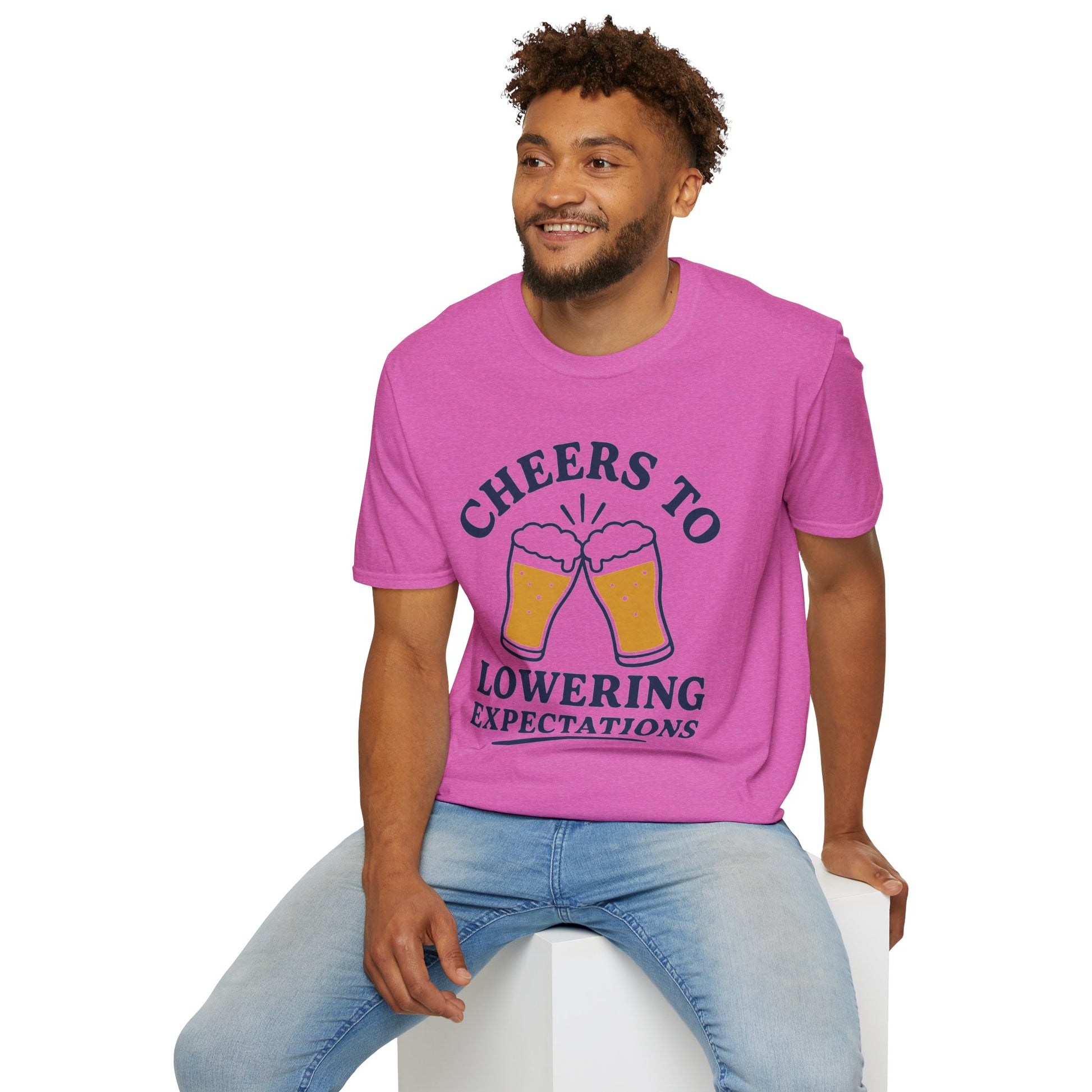 Cheers to Lowering Expectations Shirt, Heather Berry pink, worn by a model seated on a white block
