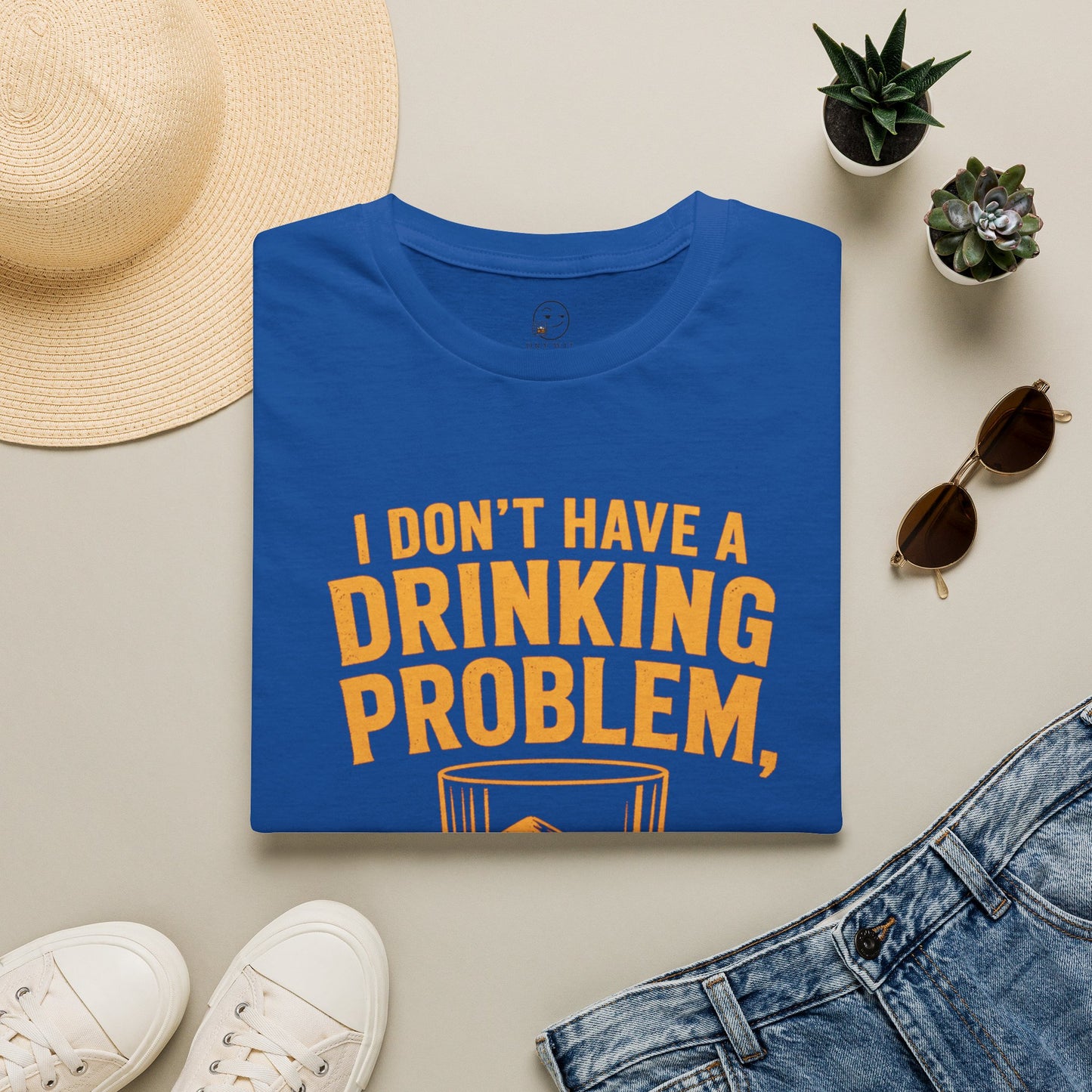 I Don't Have a Drinking Problem Shirt, Royal, folded flat lay styled with a straw hat, sunglasses, sneakers and denim
