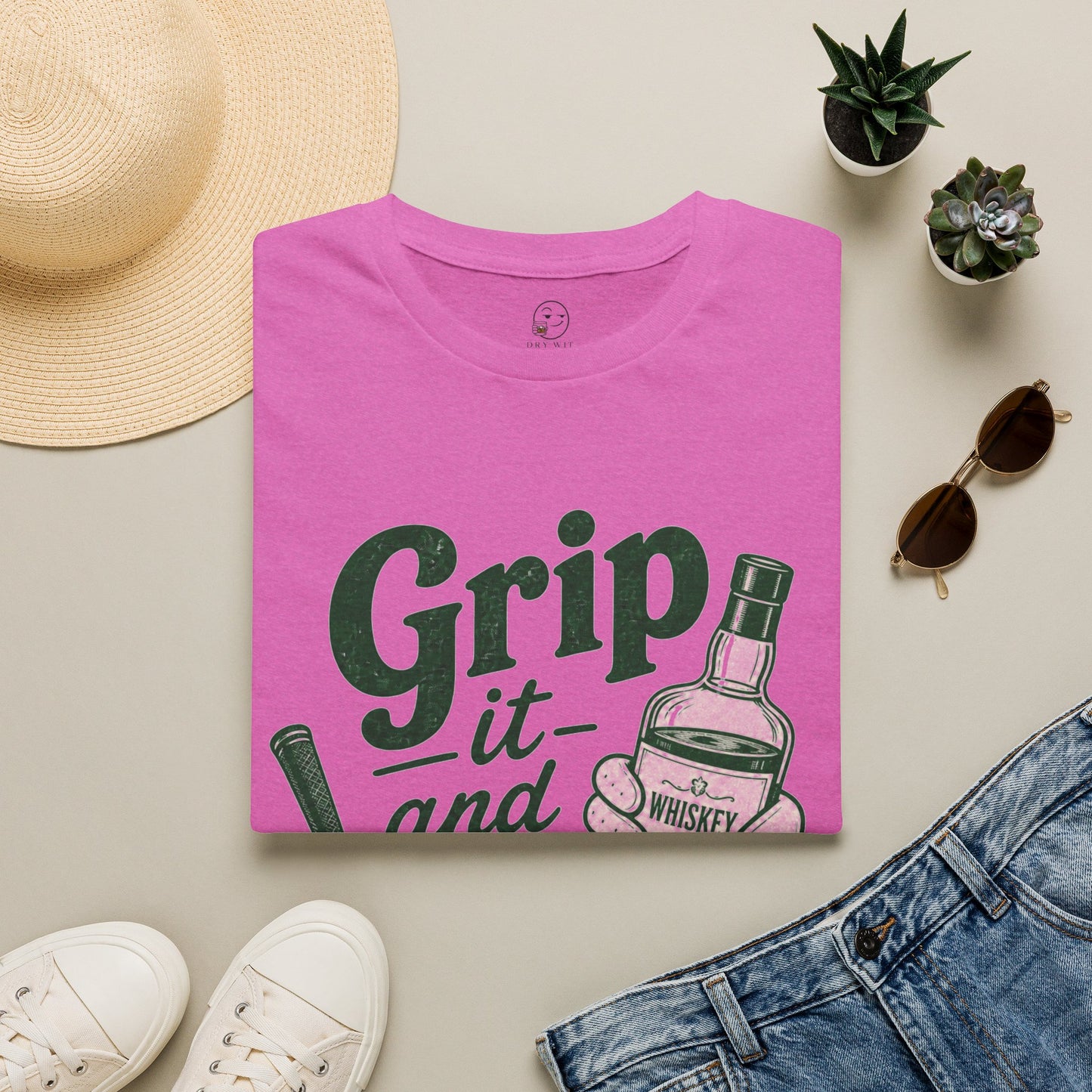Grip It and Sip It funny golf whiskey shirt, Heather Berry pink, folded flat lay styled with a straw sun hat, sunglasses and sneakers
