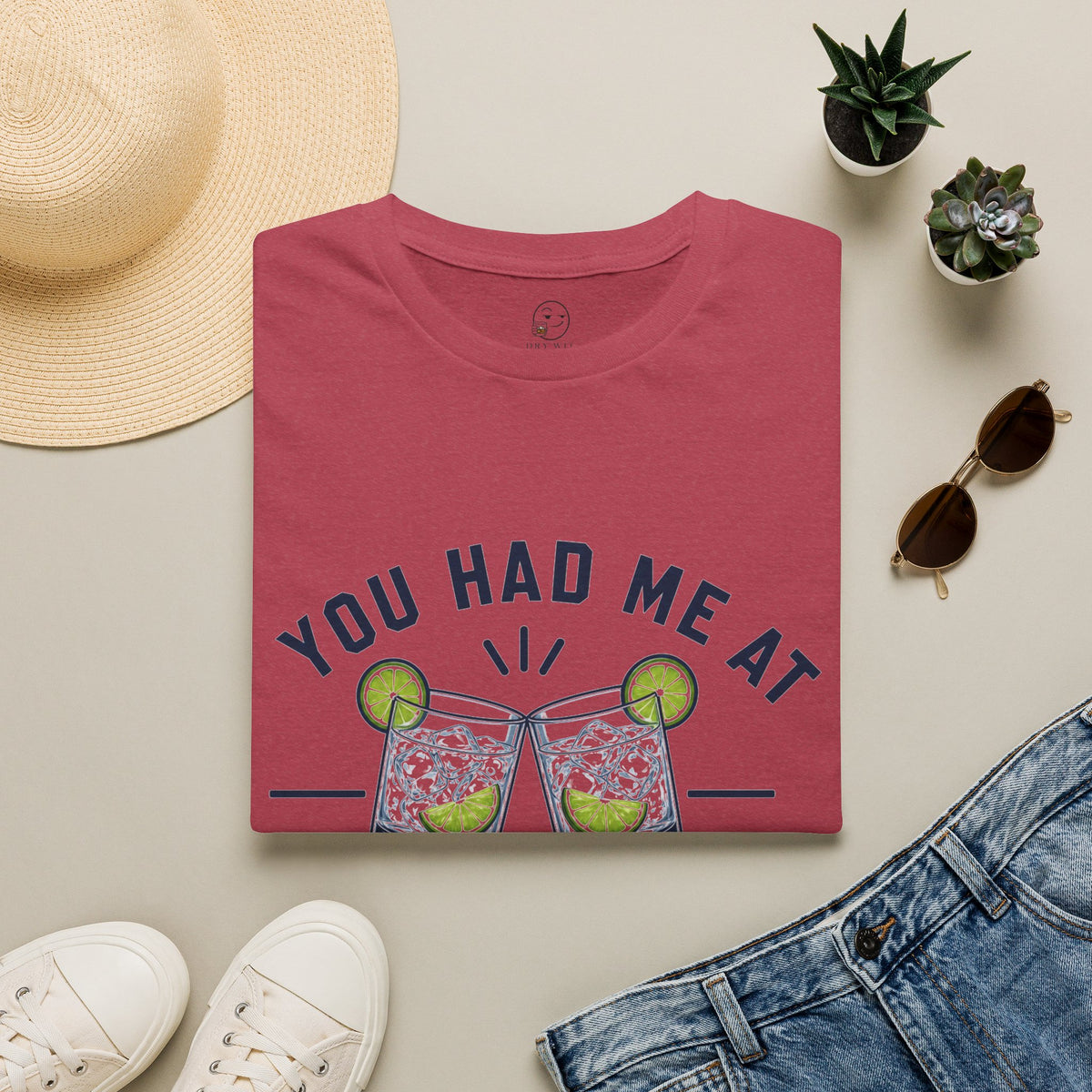 You Had Me At Happy Hour Shirt, Heather Cardinal red, folded flat lay styled with a straw hat, sunglasses, sneakers and denim