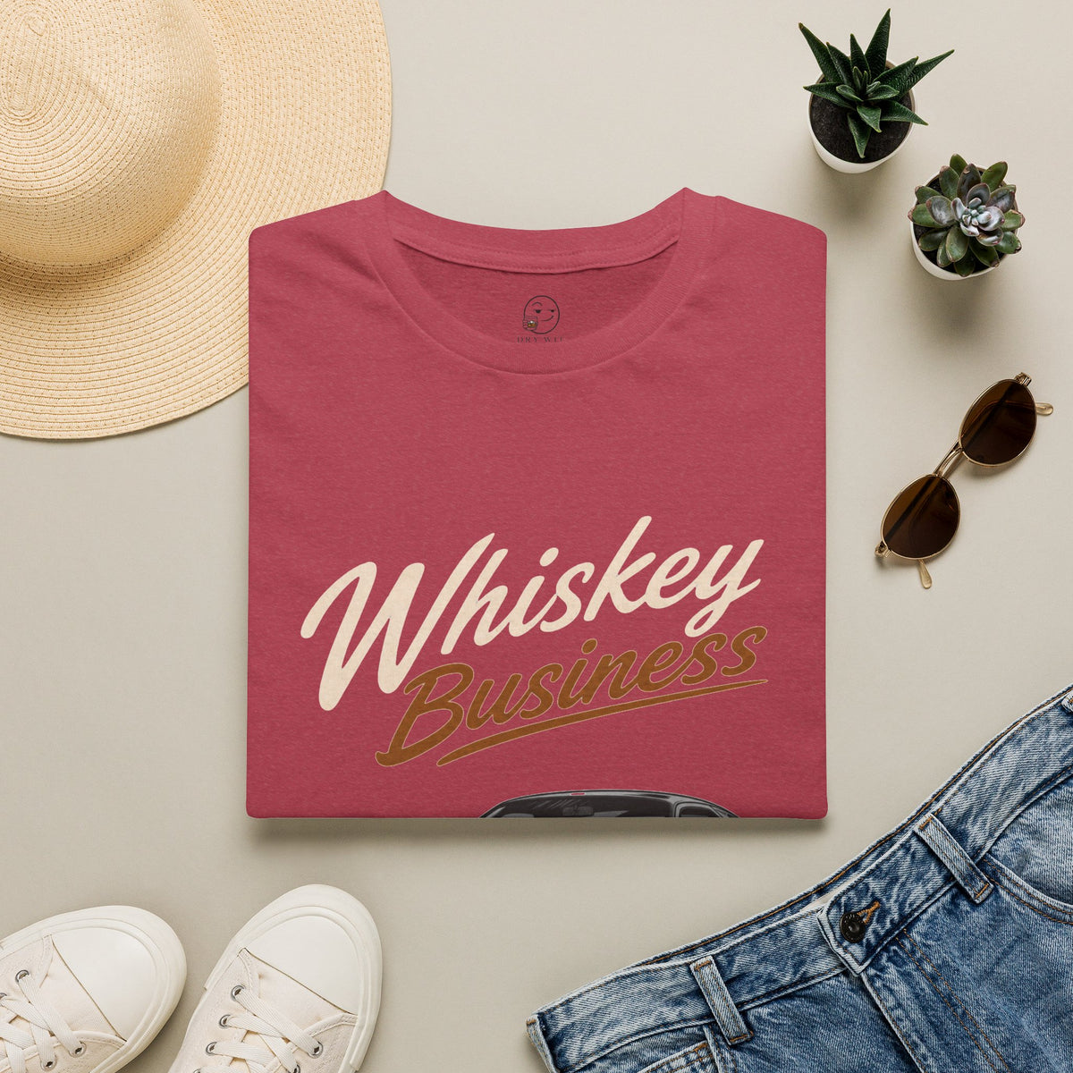 Whiskey Business Shirt, Heather Cardinal red, folded flat lay styled with a straw hat, sunglasses, sneakers and denim