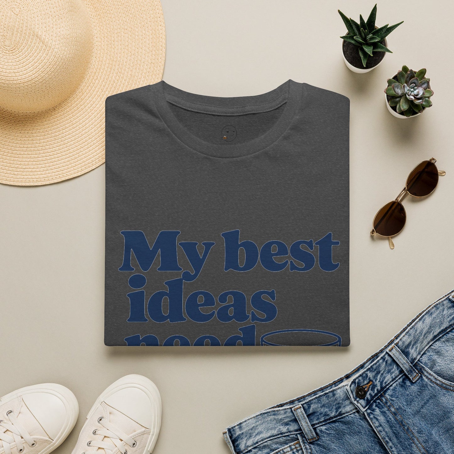 My Best Ideas Need Ice Shirt, Dark Heather charcoal, folded flat lay styled with a straw hat, sunglasses, sneakers and denim