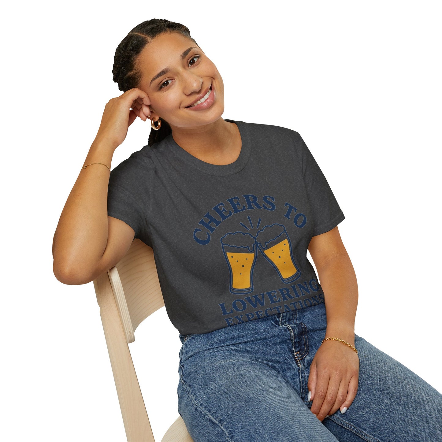 Cheers to Lowering Expectations Shirt, Dark Heather charcoal, worn by a model seated on a wooden chair