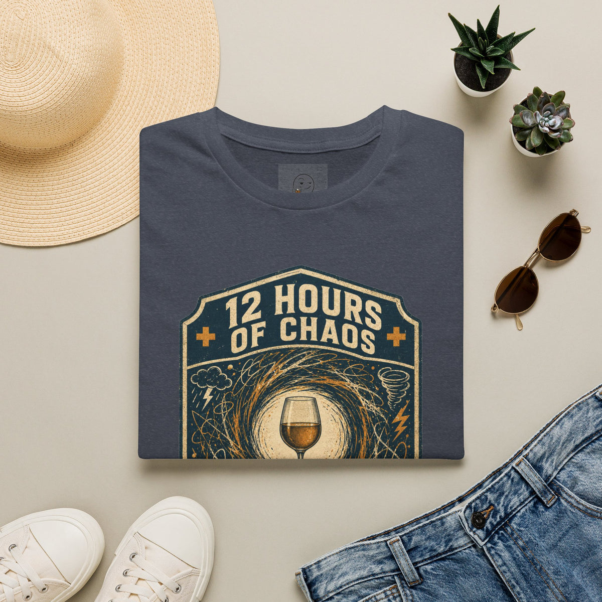 12 Hours of Chaos Shirt, Heather Navy, folded flat lay styled with a straw hat, sunglasses, sneakers and denim