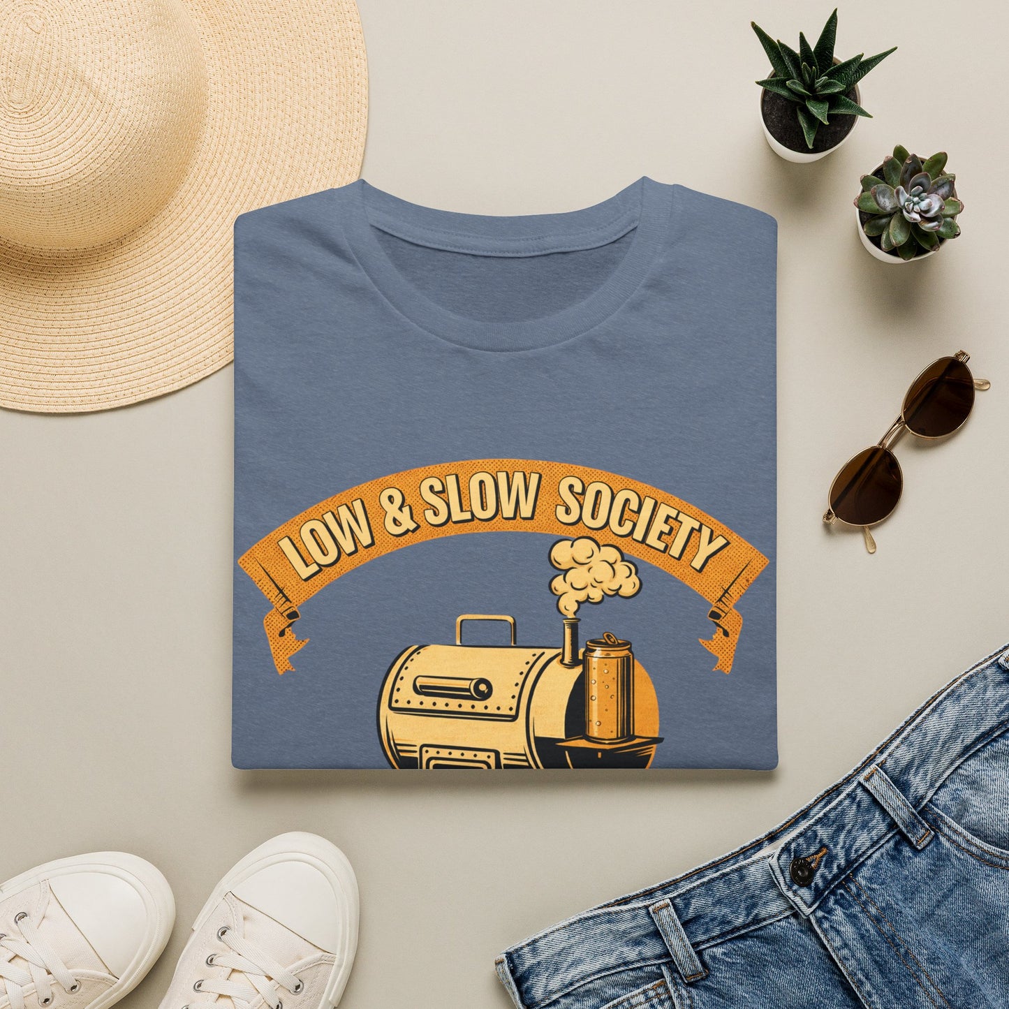 Low & Slow Society Shirt, Heather Indigo slate blue, folded flat lay styled with a straw hat, sunglasses, sneakers and denim