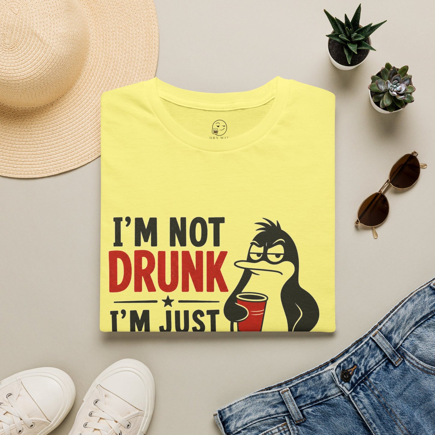 I'm Not Drunk, I'm Just Fluent in Sarcasm Shirt, Cornsilk pale yellow, folded flat lay styled with a straw hat, sunglasses, sneakers and denim