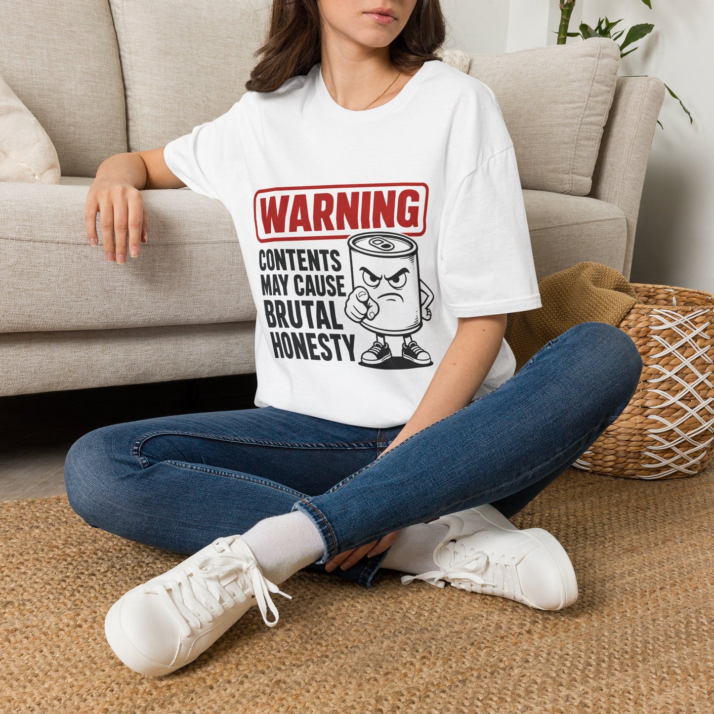 Warning: Contents May Cause Brutal Honesty Shirt, White, worn by a model seated on the floor beside a sofa