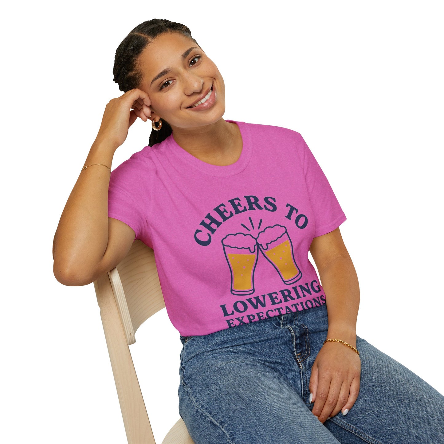 Cheers to Lowering Expectations Shirt, Heather Berry pink, worn by a model seated on a wooden chair