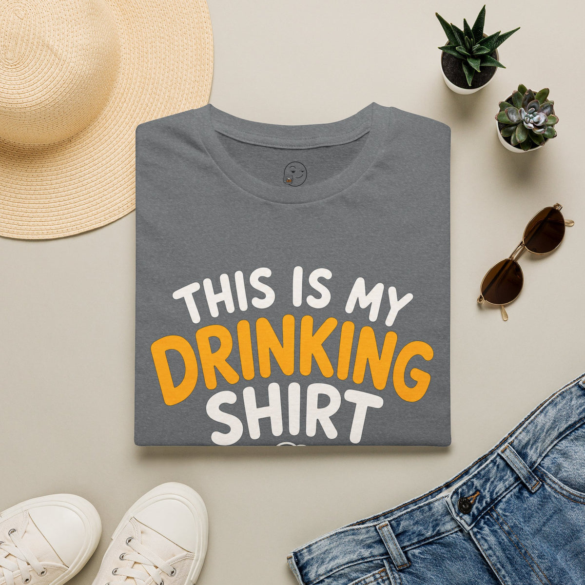 This Is My Drinking Shirt, Graphite Heather grey, folded flat lay styled with a straw hat, sunglasses, sneakers and denim