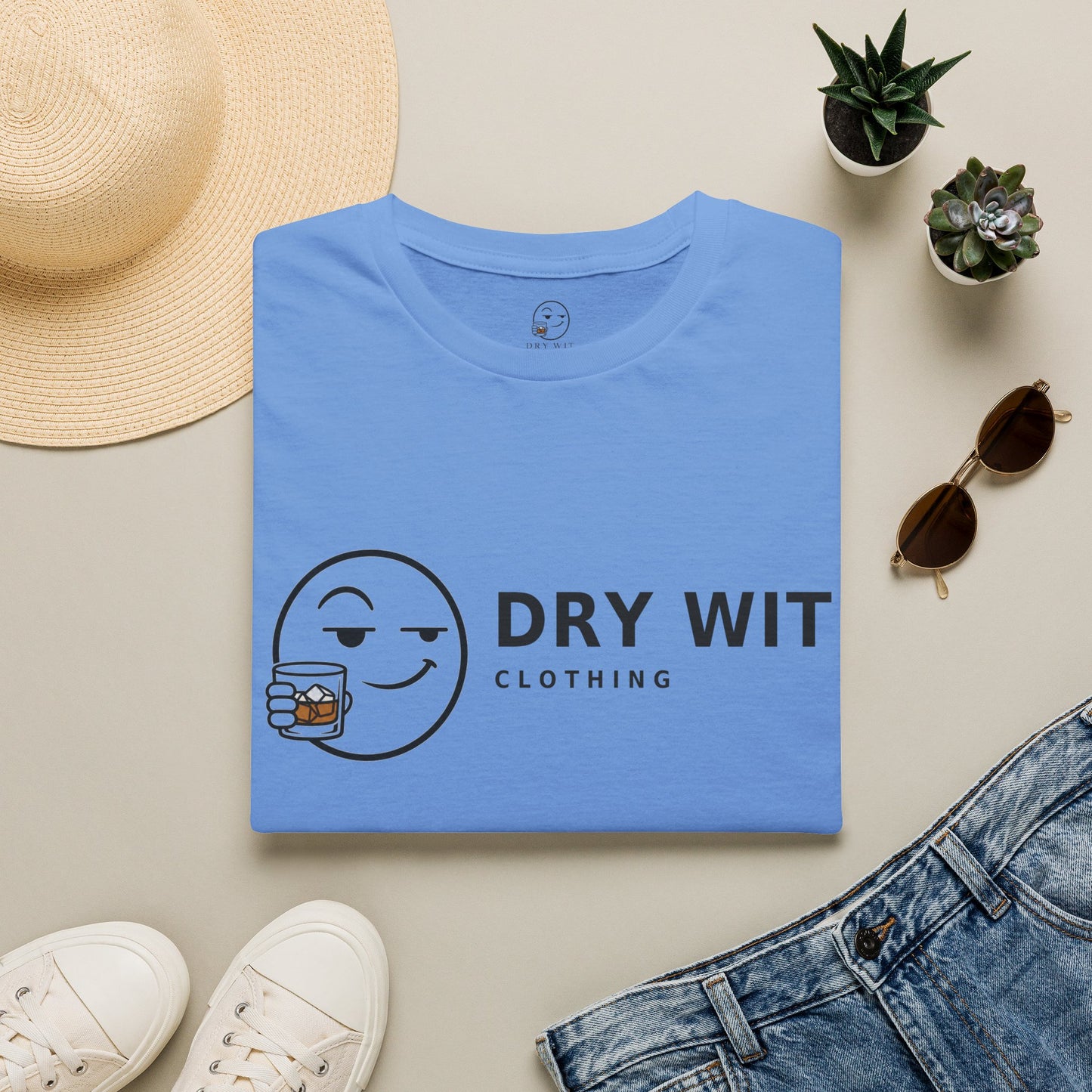 Dry Wit Logo Shirt, Carolina Blue, folded flat lay styled with a straw hat, sunglasses, sneakers and denim