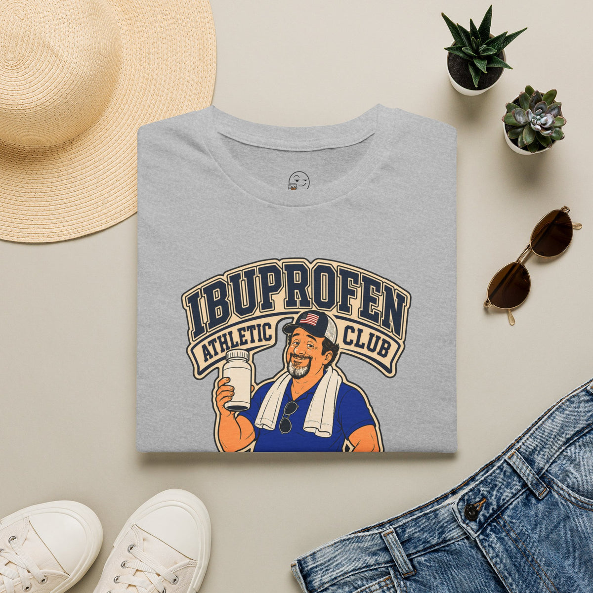 Ibuprofen Athletic Club Shirt, Sport Grey, folded flat lay styled with a straw hat, sunglasses, sneakers and denim