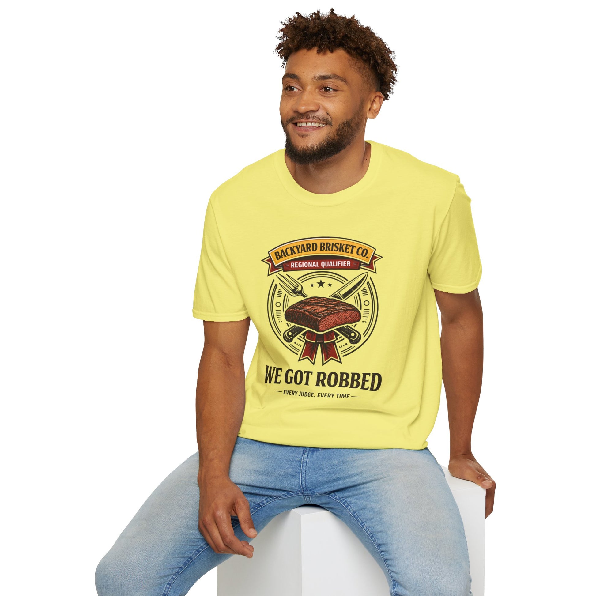 Backyard Brisket Co. Shirt, Cornsilk pale yellow, worn by a model seated on a white block