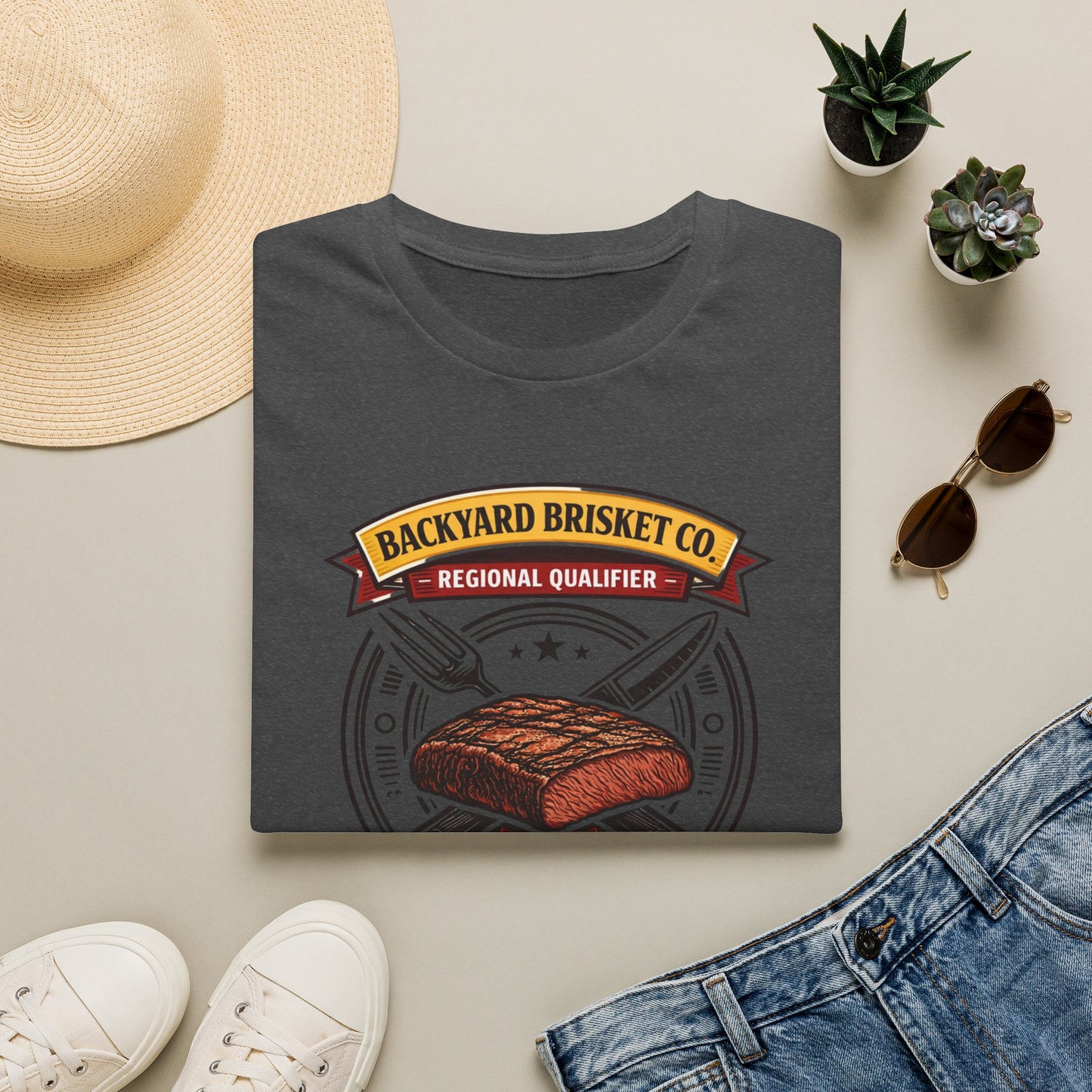 Backyard Brisket Co. Shirt, Dark Heather charcoal, folded flat lay styled with a straw hat, sunglasses, sneakers and denim
