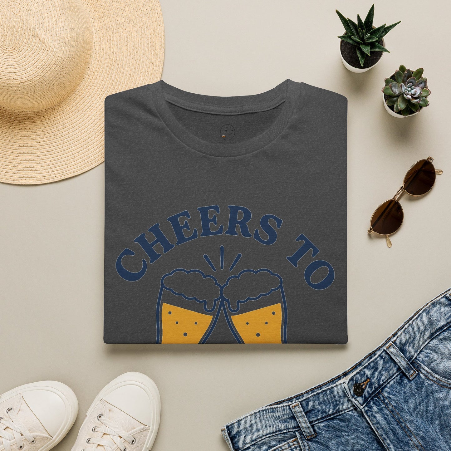 Cheers to Lowering Expectations Shirt, Dark Heather charcoal, folded flat lay styled with a straw hat, sunglasses, sneakers and denim