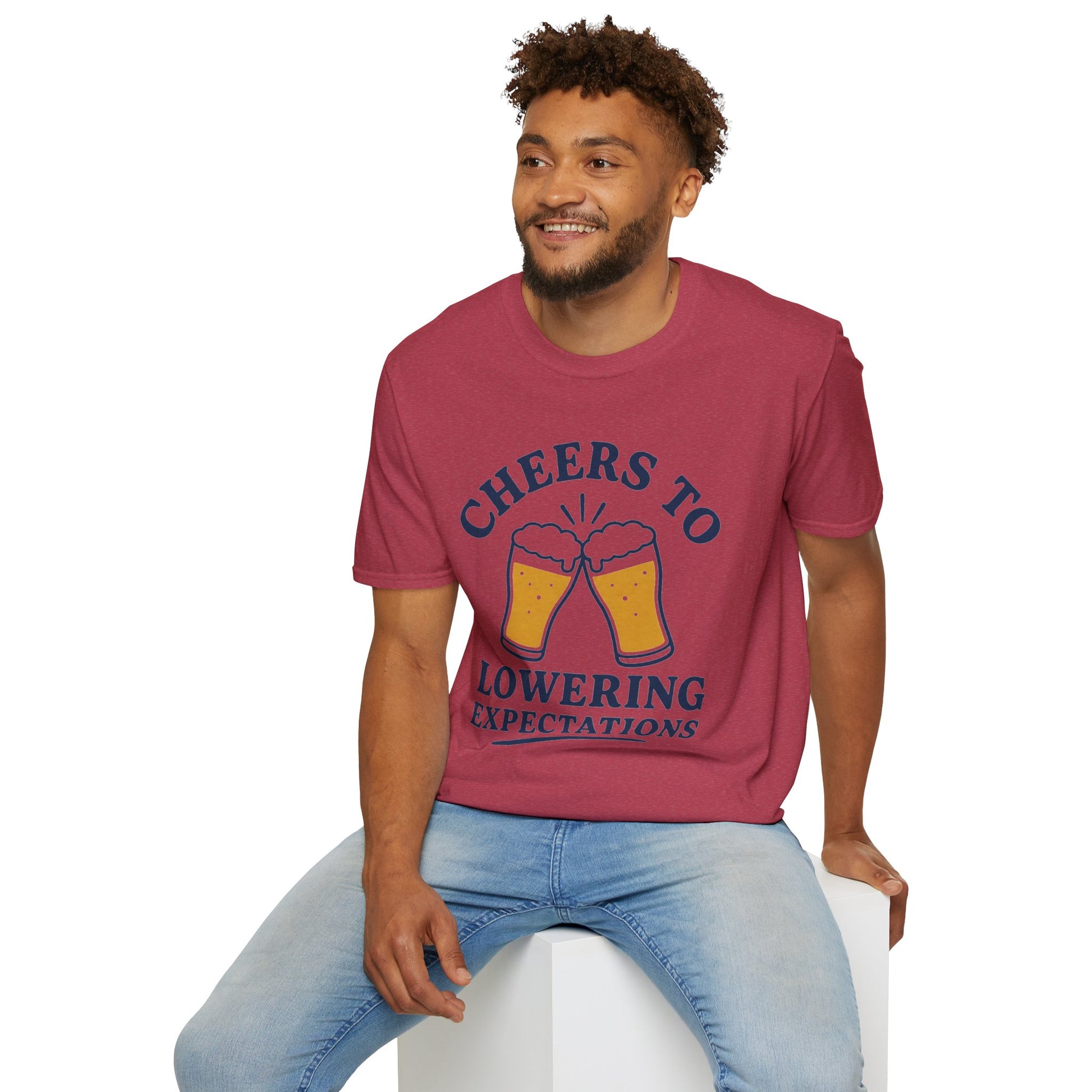 Cheers to Lowering Expectations Shirt, Heather Cardinal red, worn by a model seated on a white block