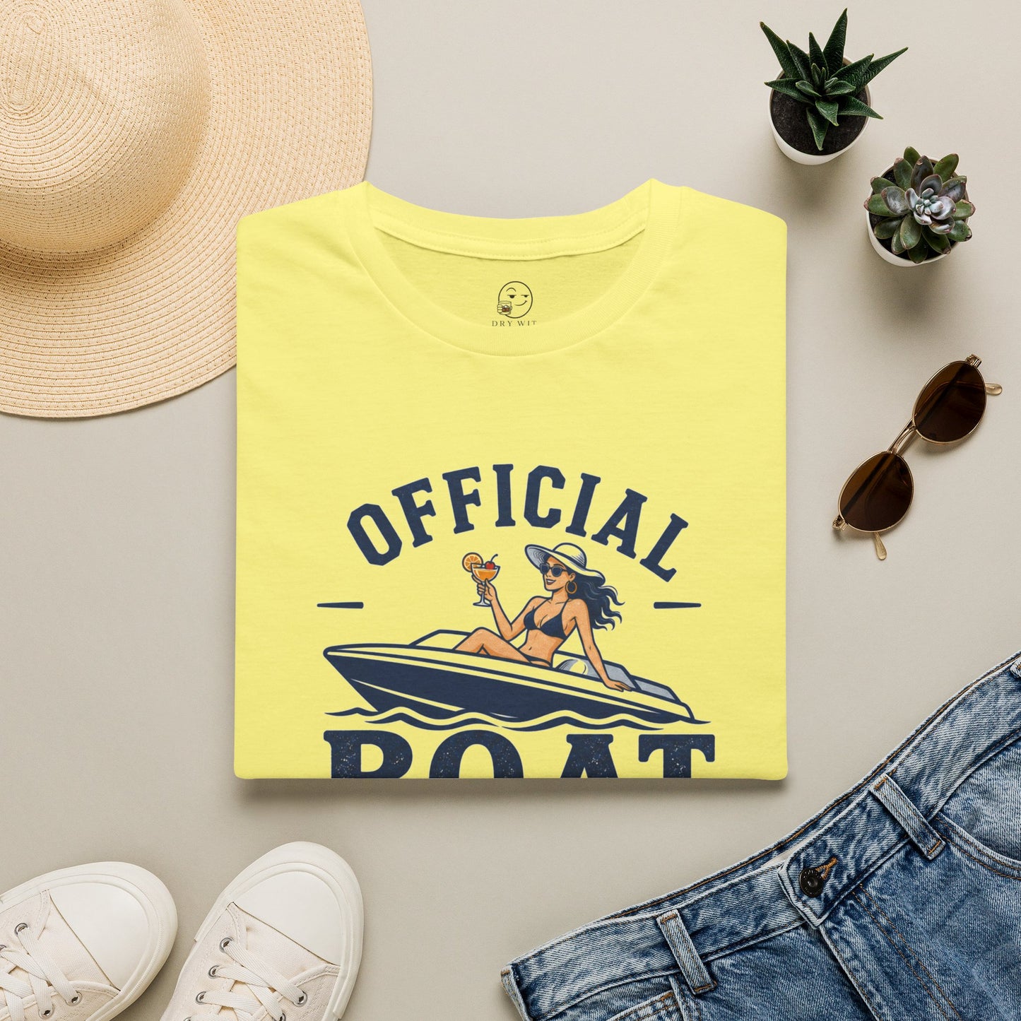 Official Boat Cocktail Drink Tester Shirt, Cornsilk pale yellow, folded flat lay styled with a straw hat, sunglasses, sneakers and denim