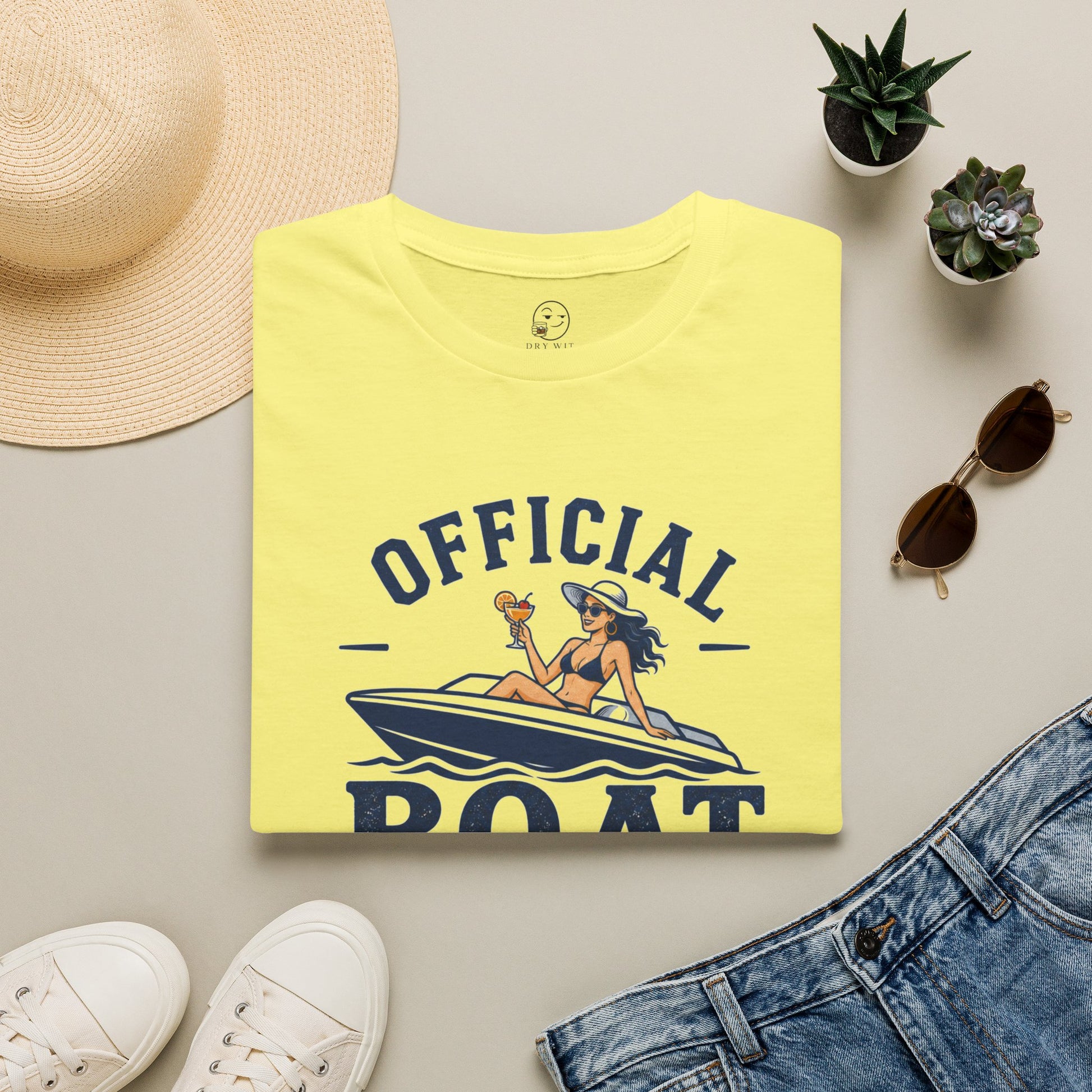 Official Boat Cocktail Drink Tester Shirt, Cornsilk pale yellow, folded flat lay styled with a straw hat, sunglasses, sneakers and denim