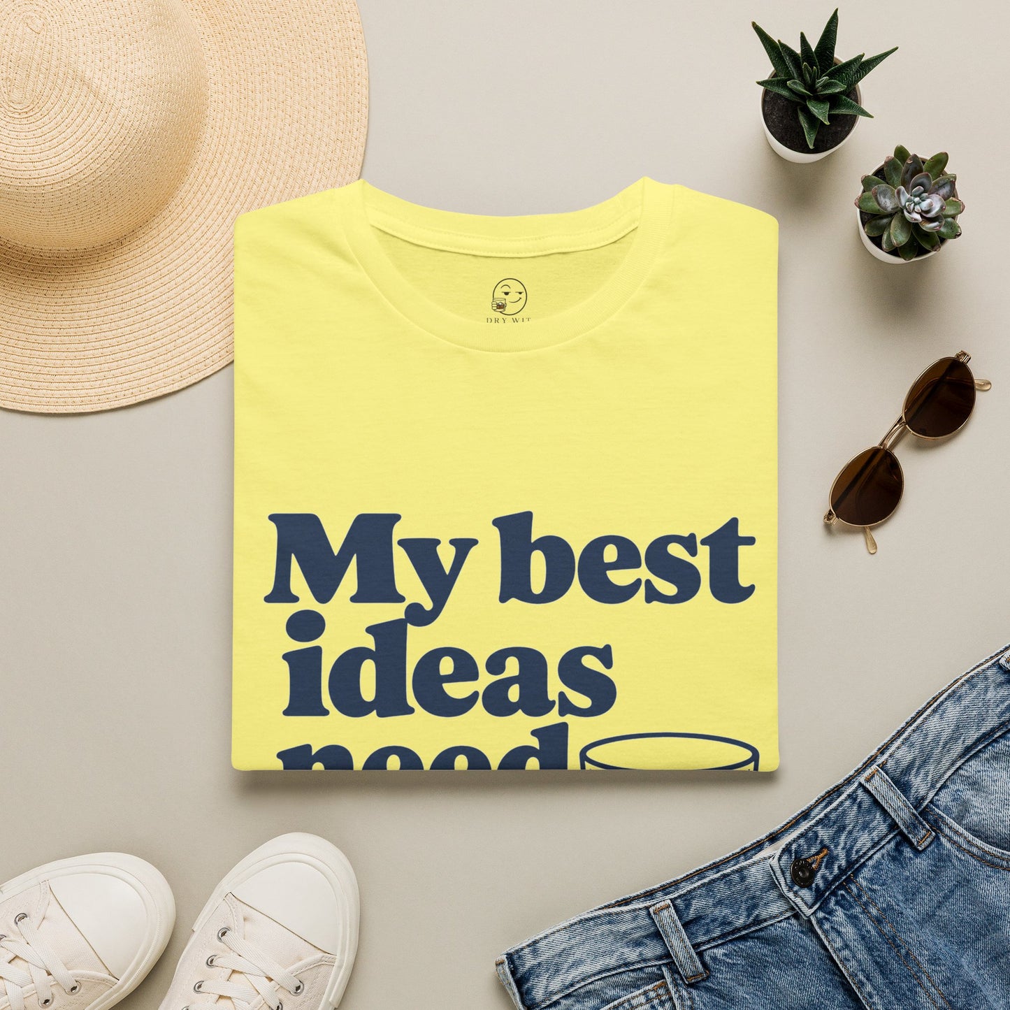 My Best Ideas Need Ice Shirt, Cornsilk pale yellow, folded flat lay styled with a straw hat, sunglasses, sneakers and denim
