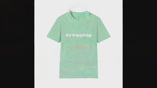 Video of a woman standing in a sunny driveway with arms crossed, giving an amused smirk toward the camera, wearing a mint green t-shirt with bold white text reading He's Golfing