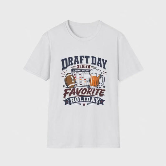 Video of a man standing in his kitchen celebrating with a raised beer while looking at a fantasy football draft board on his phone, wearing a white t-shirt with navy and maroon text reading Draft Day Is My Favorite Holiday, featuring a football, beer mug, and draft board graphic